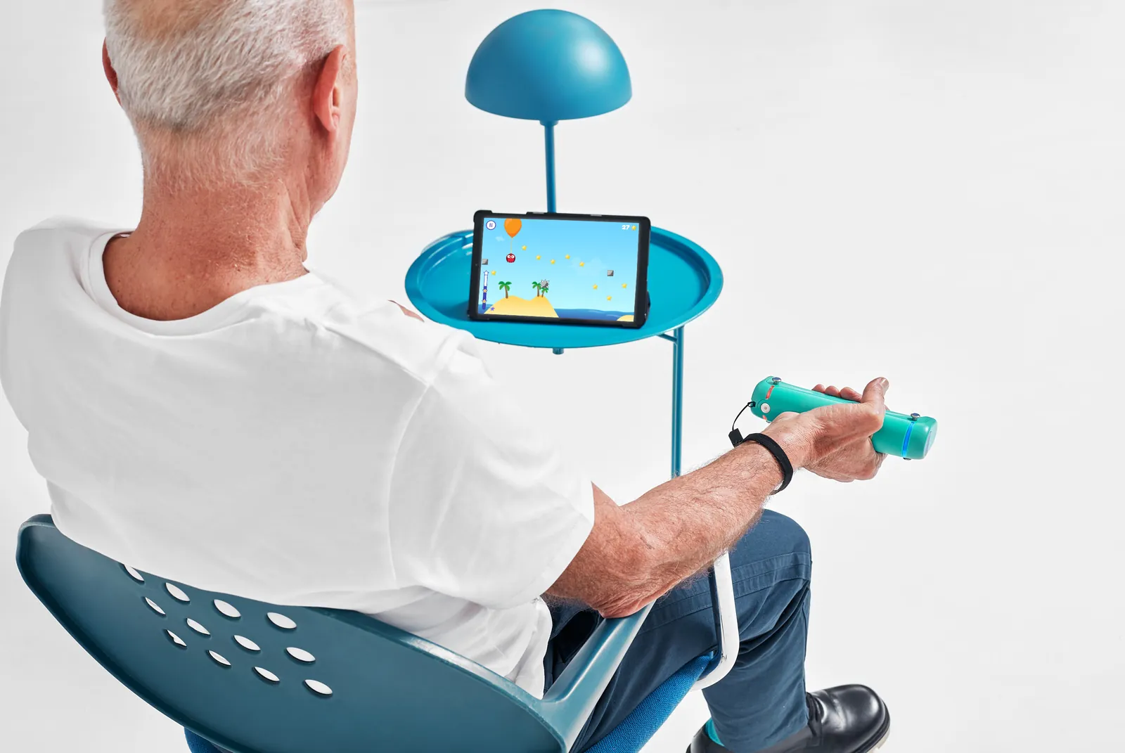 Uomo seduto che allena la presa con GripAble giocando a Balloon Buddies sul tablet