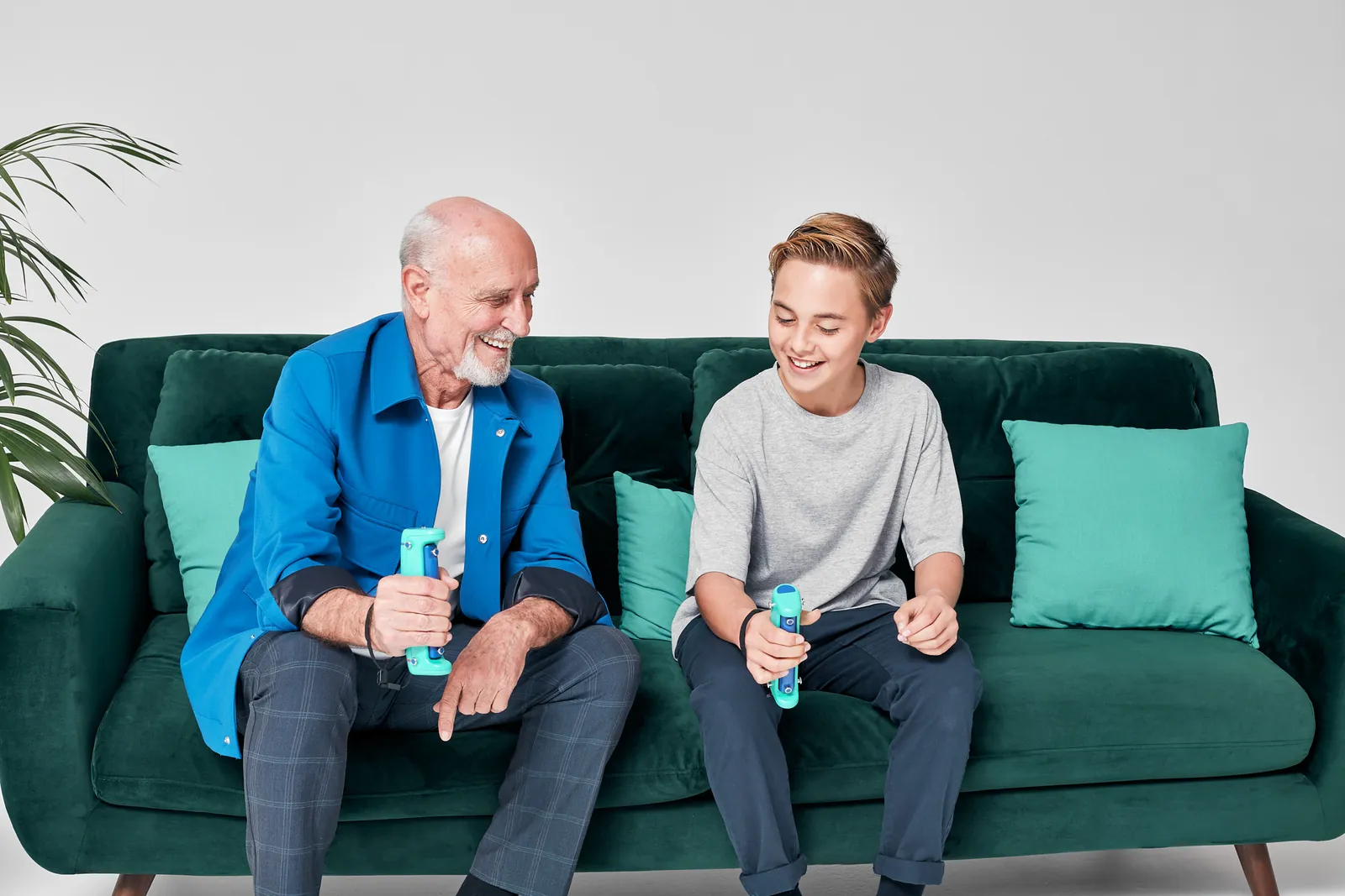 Nonno e nipote sul divano che si allenano insieme con due dispositivi GripAble